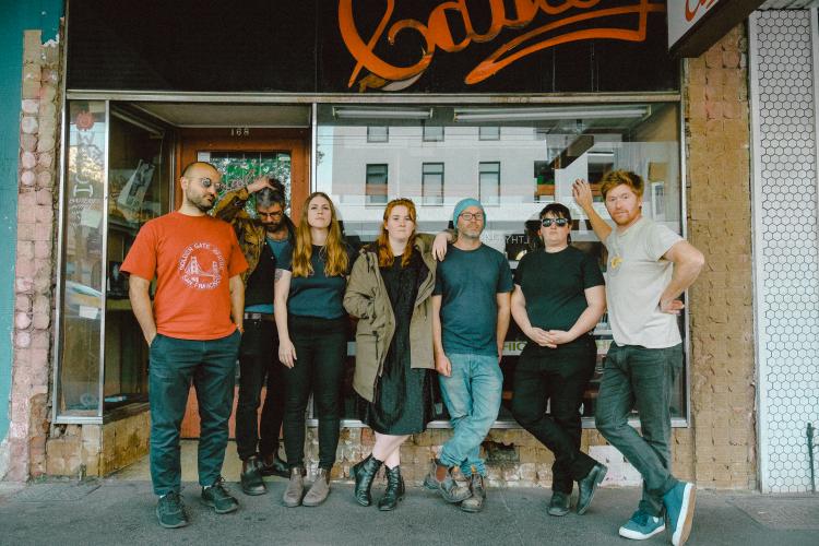 Cash Savage and The Last Drinks standing outside a shop front posing for the camera