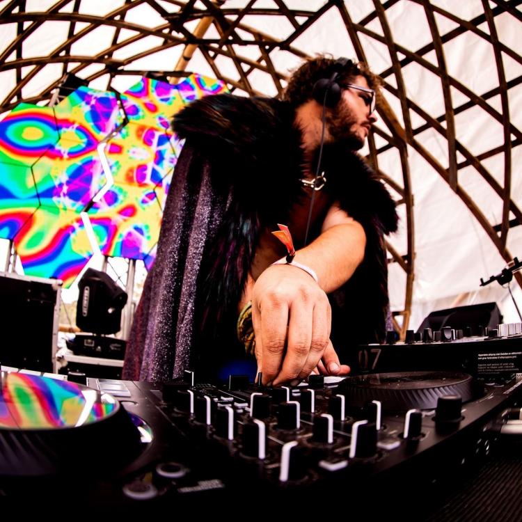 Jamie Forest DJing live in a fur jacket in front of a multi-colored background
