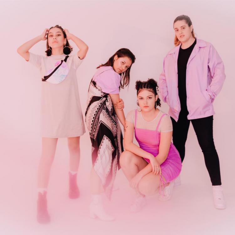 The 4 members of Pink Matter posing in front of a pink background