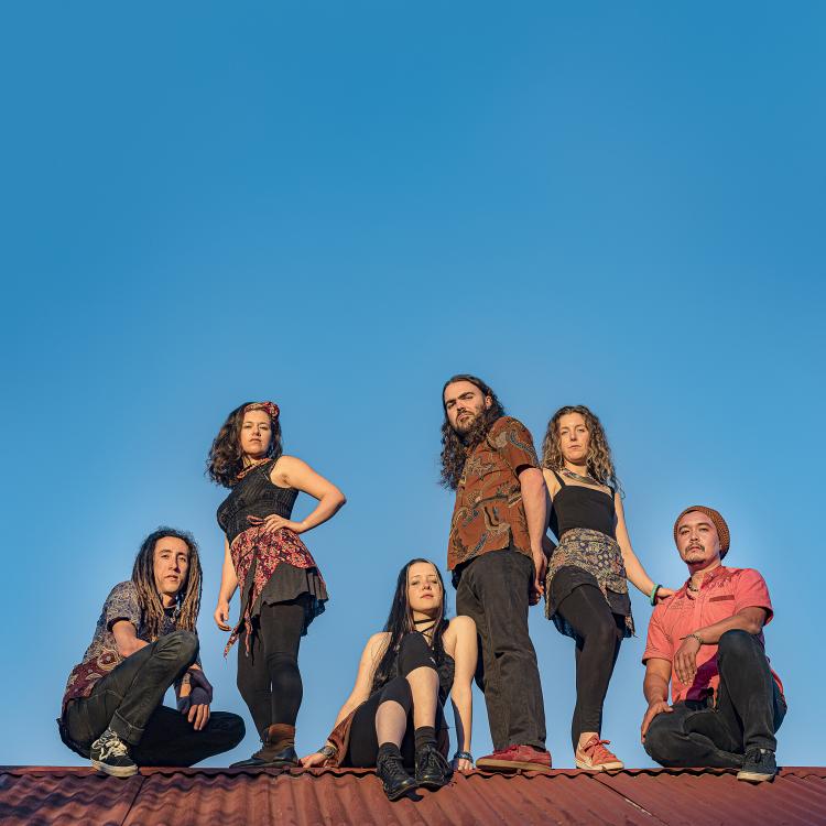 Rhythm Hunters posing on a roof with the blue sky behind them. All members are at various levels