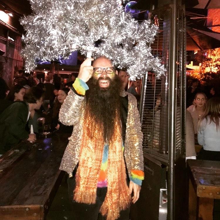 Man with beard holding Christmas tree above his head