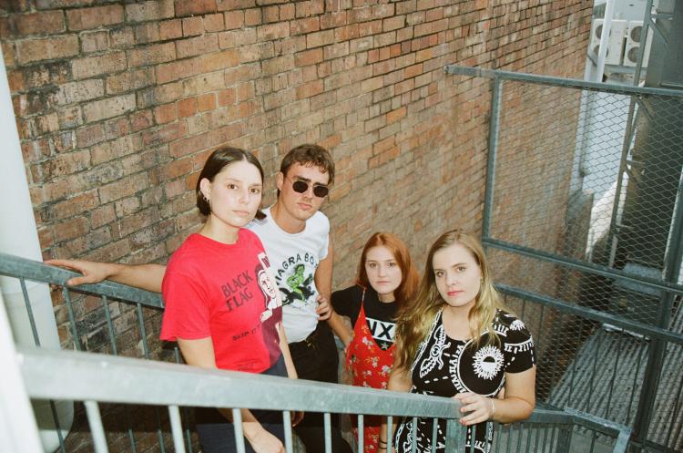 The four members of Perve Endings standing on a staircase looking up at the camera, with the second member wearing a white shirt and glasses.