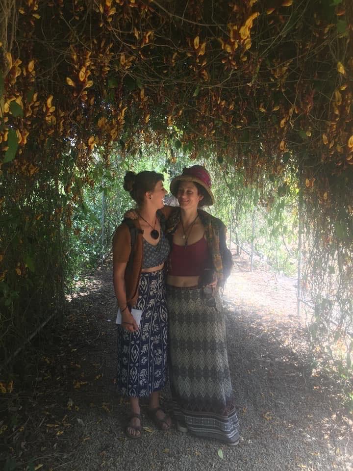 Two women standing under a tree embracing
