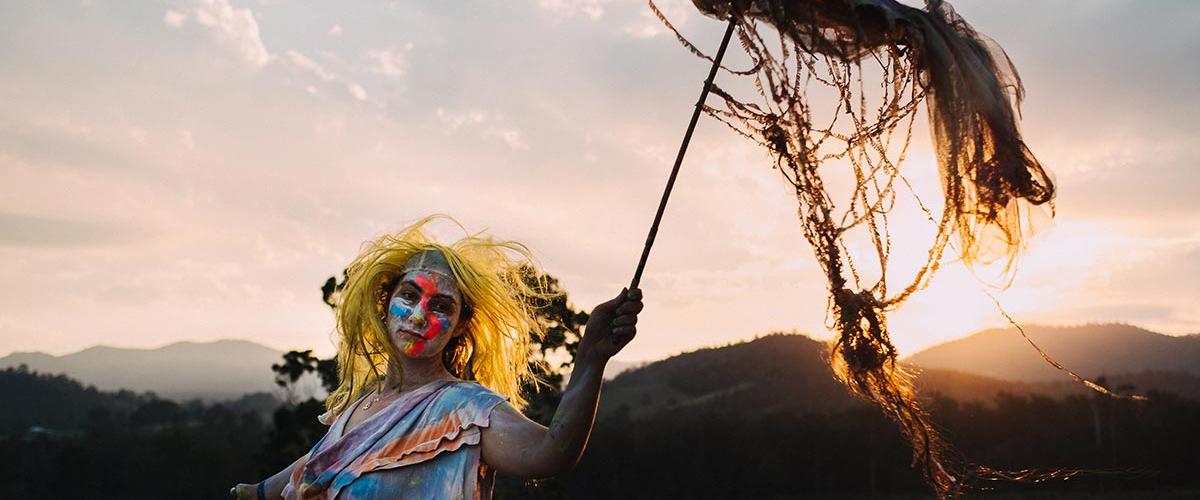 Jungle Love Festival a performer dressed in makeup performing at sunset